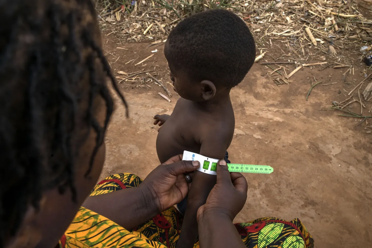 Uwase Christine, a Village Health Team (VHT) volunteer, screens 3-year-old Mutuyimana Raphael during a home visit in Kabazana B, Nakivale Refugee Settlement in Isingiro District, Uganda, on September 9, 2026. Raphael has been receiving care for severe acute malnutrition and is steadily recovering with continued nutrition support and follow-up from Uwase.