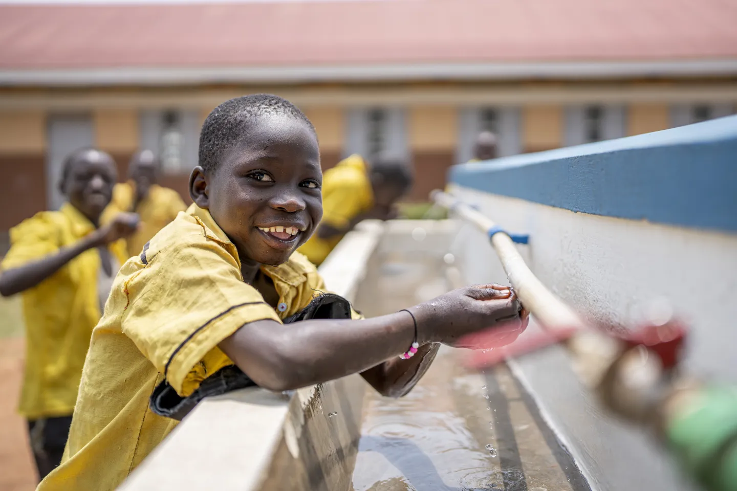 Mukatijiro Walter, 8, a P3 student, enjoys drinking water from the newly constructed hand washing facility at Aria Primary School, Terego district.