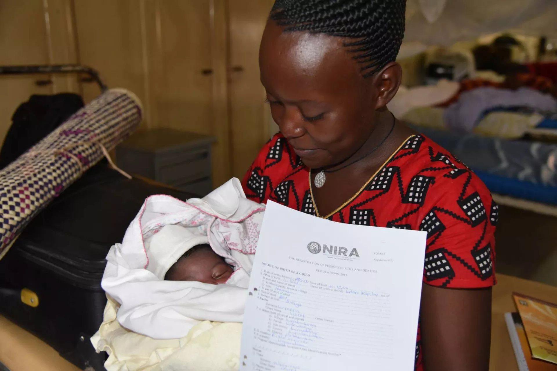 A mother holds a baby and a certificate of birth registration