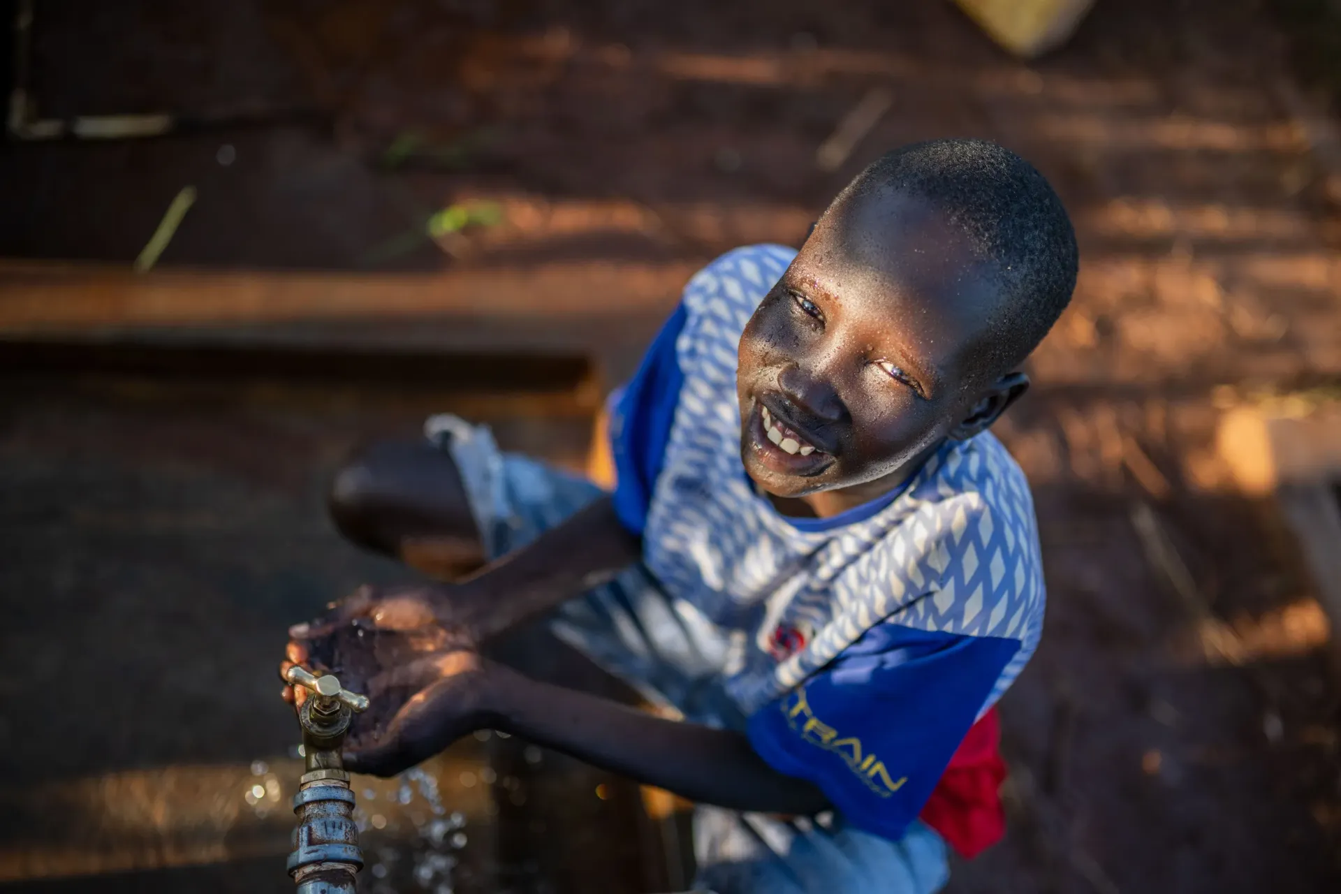 Eleven-year-old Laul Marol drinks clean water from a UNICEF tap stand funded by the European Union in Cluster I, Kiryandongo Refugee Settlement, October 14, 2025. Like Marol, children across the settlement race toward the sound of rushing water, their laughter echoing through the camp as they drink, splash their faces, and wash dust from their legs&mdash;simple joys made possible by access to safe, running water.