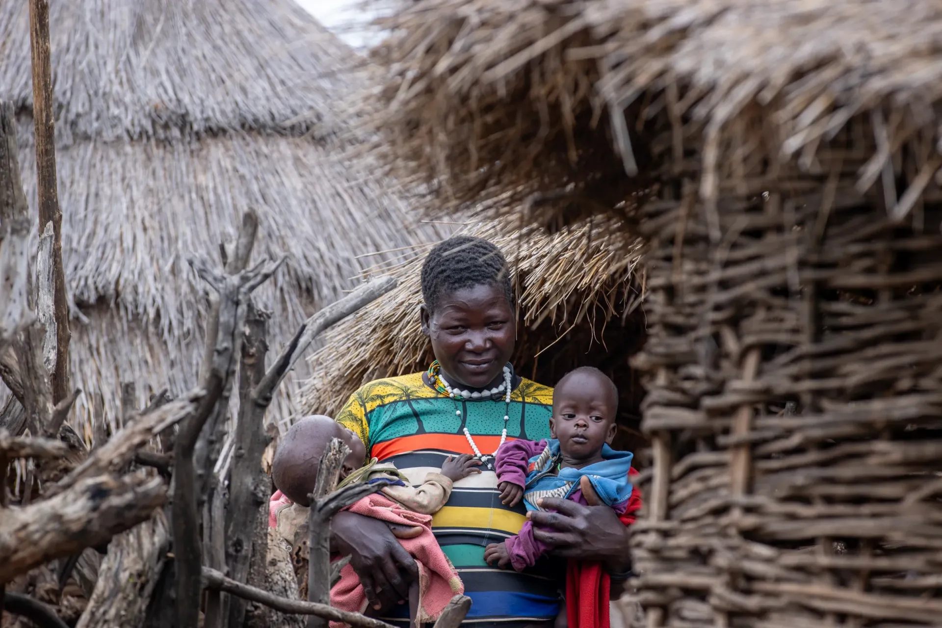 Lokol Regina holds her twins outside their home in Leterwa village, Kaabong. Both children are now enrolled on RUTF at Kopoth HCIII and are gaining weight.