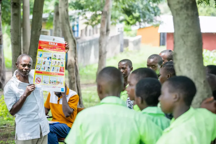 Byaruhanga Patrick, the District Health Educator, Ntoroko District engaging pupils of Karugutu Primary School with Ebola disease posters in order to increase awareness about the disease in the school.