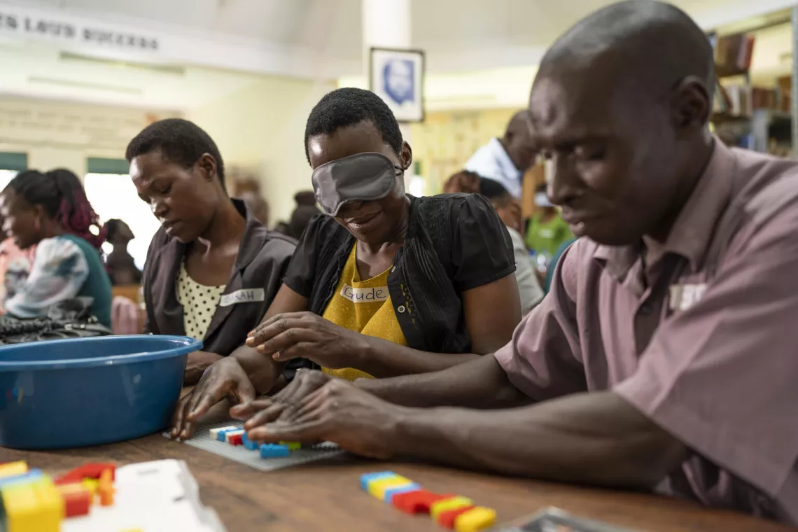 Kumukyaya Sarah (L), Nabwire Gertrude (Middle) and Kibumba Jude participate in a training exercise with the Braille bricks. 