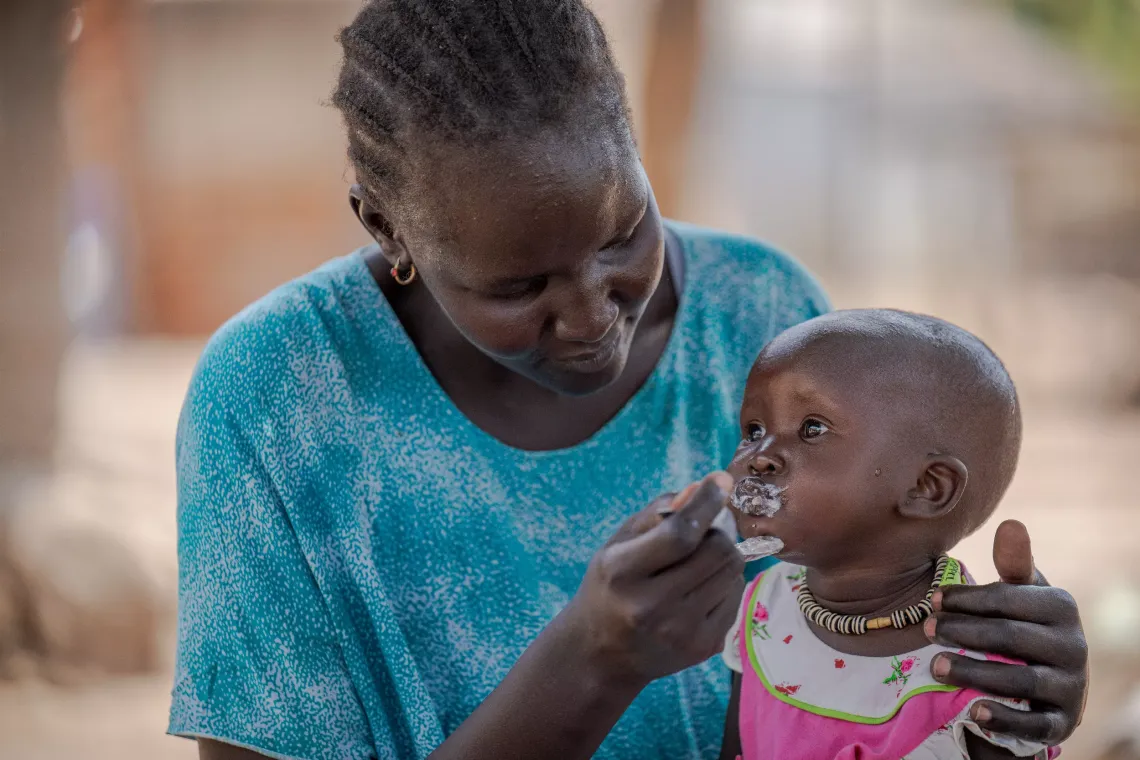 Aguer Deng 1 year old being fed by her caretaker while at home in Nyumanzi Refugee settlement.