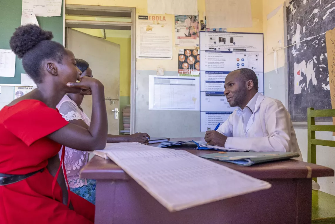 22-year-old Prossy Mirembe (in red) and fellow YAPs peer, Judith, (left) interact with their supervisor, Bashir Basutaine, Psychiatric Nurse, at Nankandulo Health Centre IV, Kamuli District, 8 May 2025.