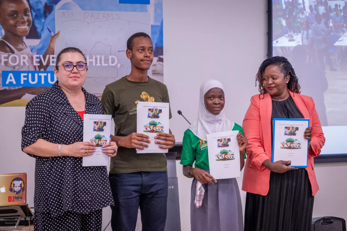 A commemorative photograph captures key participants from the National Children Climate Dialogue, including Barno Mukhamadieva (UNICEF Uganda's Chief of Basic Education and Adolescent Development), Ms. Anastasia Namululi (Ministry of Water and Environment representative), and young delegates Atwine Presely and a fellow participant. The children are prominently displaying their Children's Declaration Document and Call to Action from the climate dialogue.