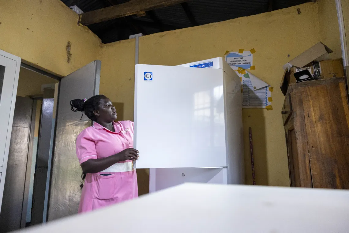 A health worker picks vaccines from the cold room at Amomwa Health Centre III, Dokolo District. The Health Facility Solar Electrification project, funded by Gavi and implemented by UNICEF with the Ministry of Health and WHO, strengthens immunisation delivery by ensuring uninterrupted power for vaccine storage.