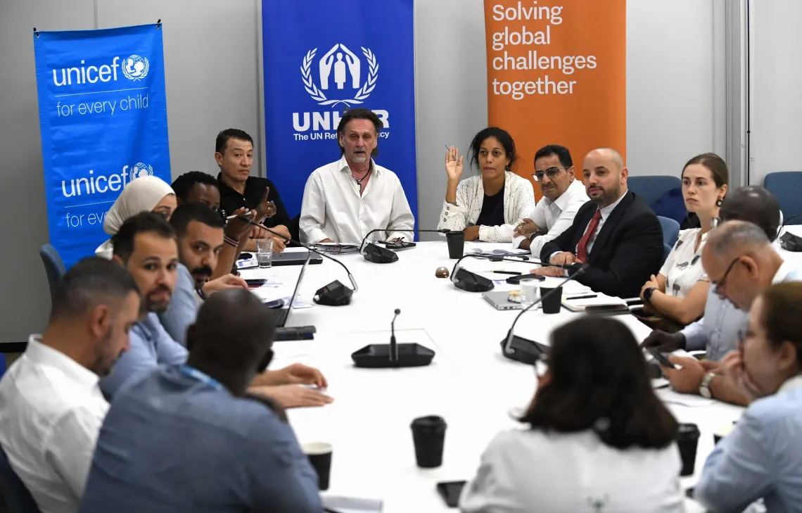 A cross section of multinational delegates from UNICEF, UNHCR and government in a group discussion on mainstreaming refugees into national development. 