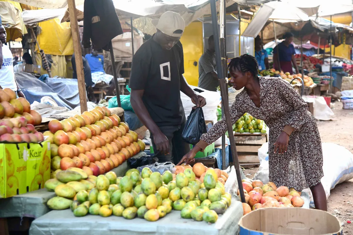 Ndibalekera Maria Judith, one of the beneficiaries of the Girls Empowering Girls program, shops for mangoes for her fresh juice business at a market in Kisenyi Zone in Kampala city.