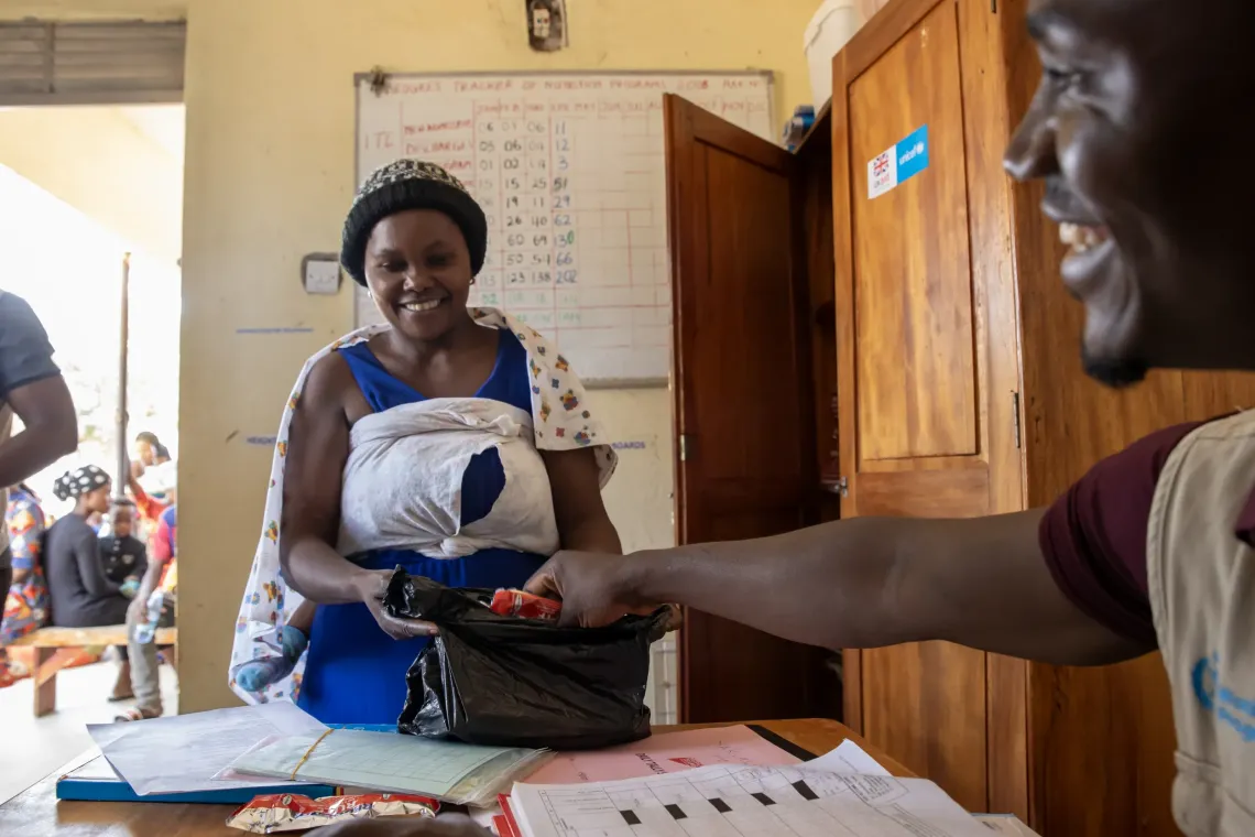 A mother receives a supply of Ready-to-Use Therapeutic Food (RUTF) for her child at Nyarugugu Health Centre in Nakivale Refugee Settlement, Isingiro District. Children enrolled in outpatient therapeutic care receive a week's ration at each visit and return weekly until they recover. The supplies are provided with support from the Uganda Humanitarian Fund, through UNICEF.