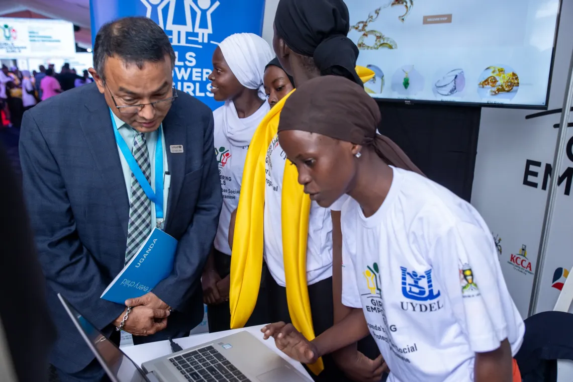 Dr Robin Nandy, UNICEF Representative to Uganda, takes in what a beneficiary is showcasing on her laptop during a visit to her stall at the Girls Empowering Girls close-out event, City Hall, Kampala, 17 April 2026. 