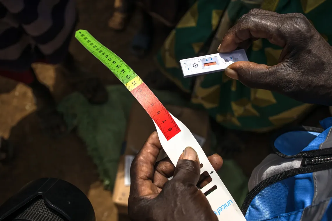 Lotee Mariko, 50, a Village Health Team (VHT) member, holds a mid-upper arm circumference (MUAC) tape and a rapid malaria test kit during door-to-door health and nutrition visits in Longoleki village, Moroto District, Uganda, on August 10, 2026. 