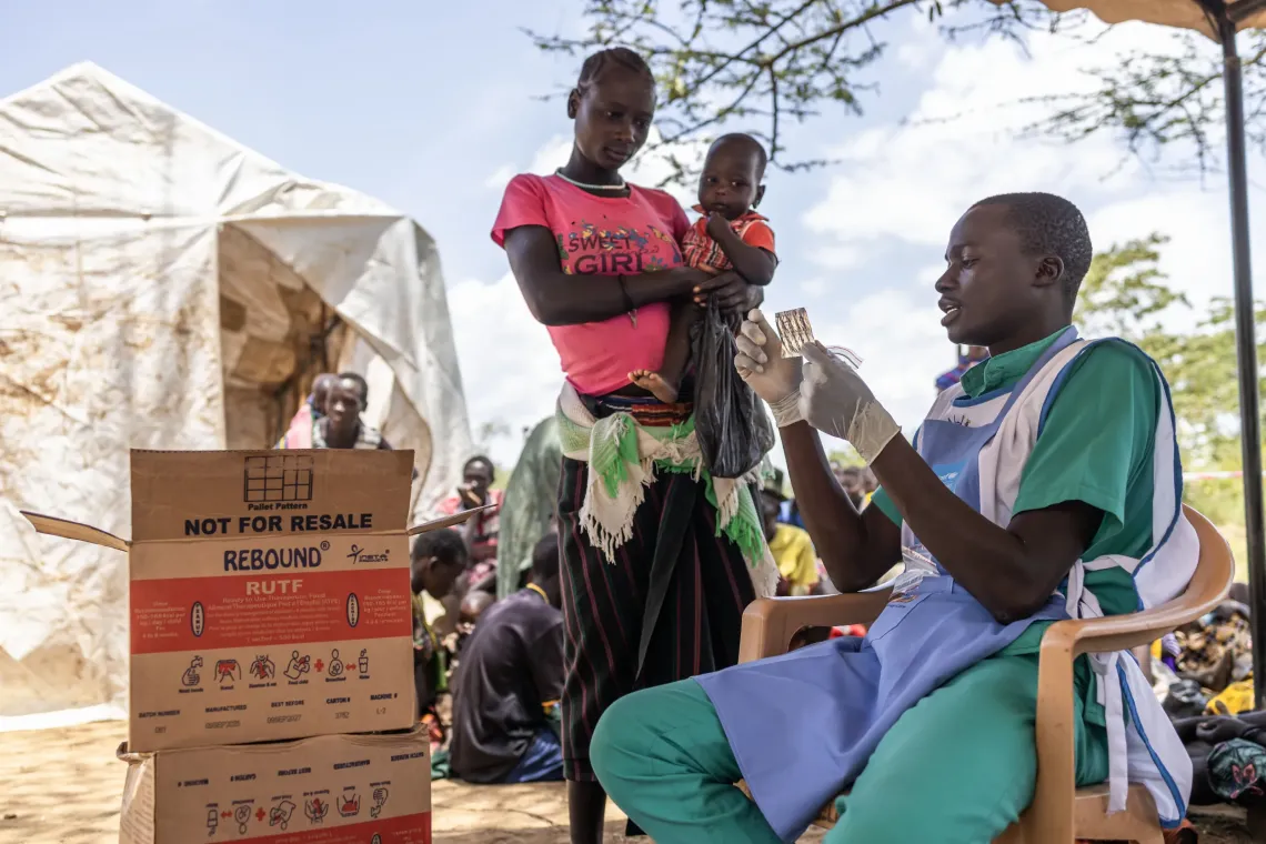 A health worker attends to a caregiver at Nakatapan Outpost in Lolelia South, Kaabong District, Uganda, on August 11, 2026. The outpost brings integrated health and nutrition services, including treatment for acute malnutrition, closer to families who would otherwise travel long distances to a health facility. 