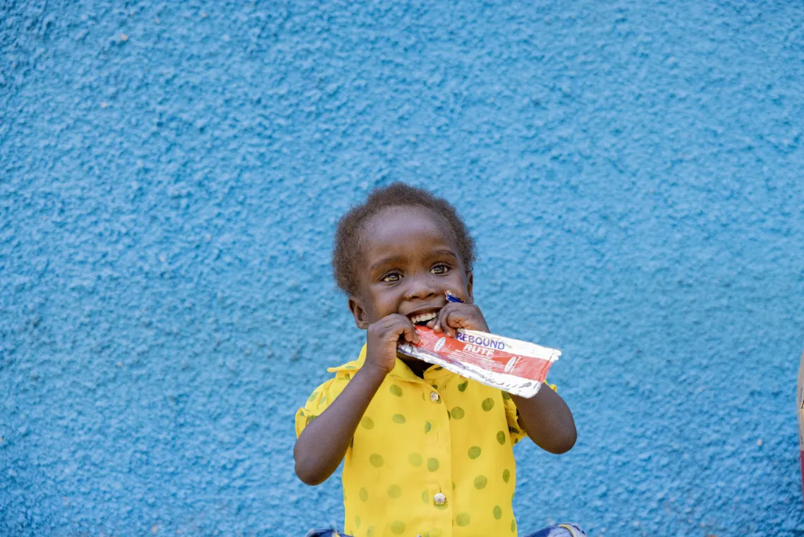 Three-year-old Stella Paibe eats from a sachet of the Ready-to-Use Therapeutic Food (RUTF) at Uriama Health Centre III in Terego District, Uganda.