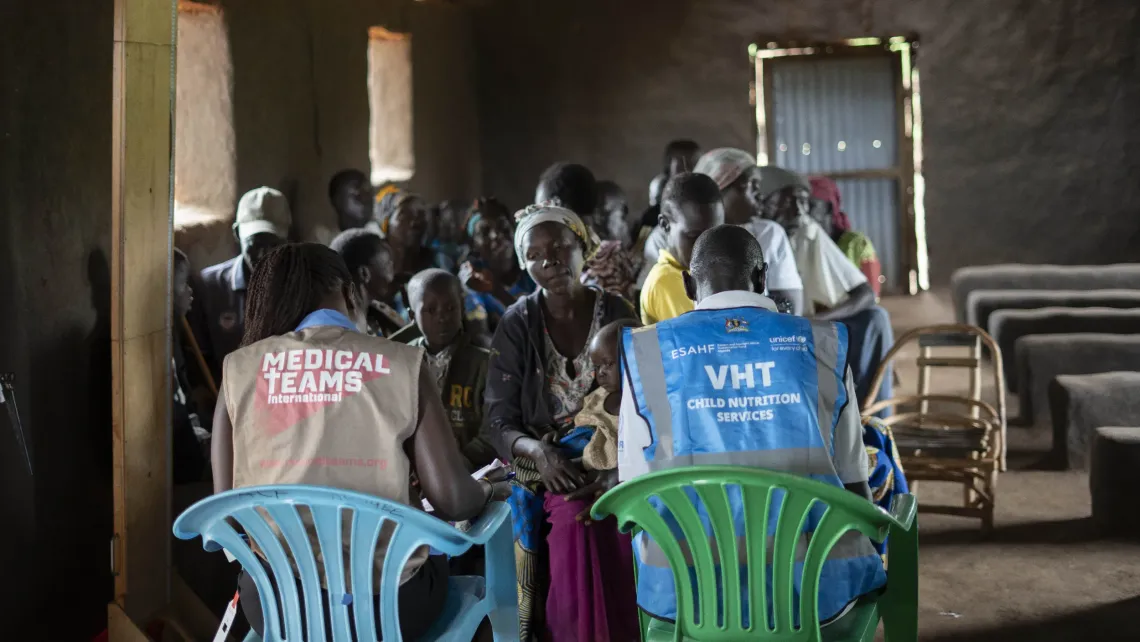A nutritionist from Kombge Health Centre III and a Village Health Team (VHT) member work with caregivers during an integrated health and nutrition outreach in Bidibidi Refugee Settlement, Yumbe District, Uganda.