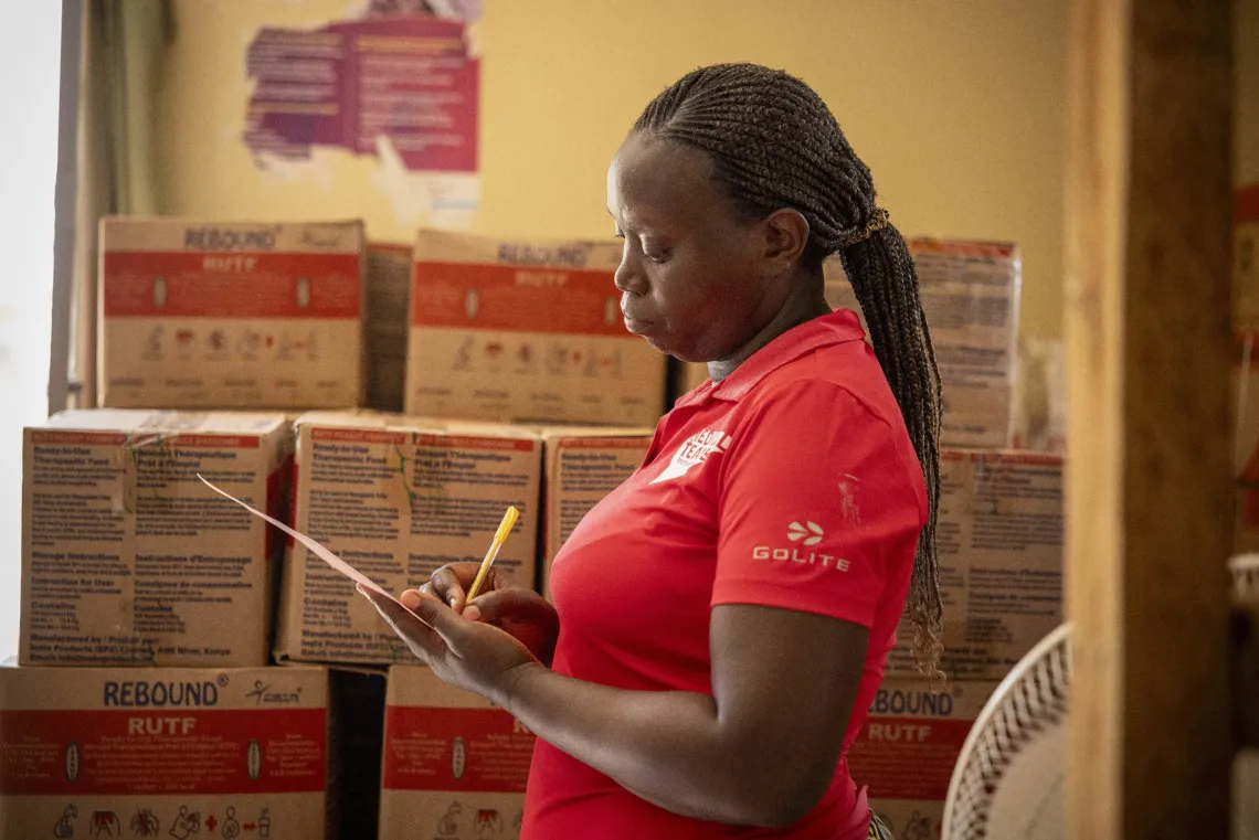 At the facility store of Uriama Health Centre III in Terego District, Uganda, Stores Assistant Susan Karungi updates the stock record for Ready-to-Use Therapeutic Food (RUTF). 