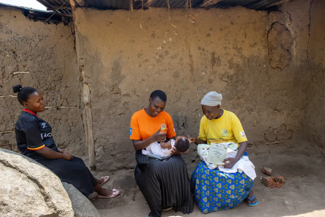 A CHEW and VHT speaks with a mother outside her home in Webuta Cell, Bumuyaga Ward, Mbale City, during a routine household visit.