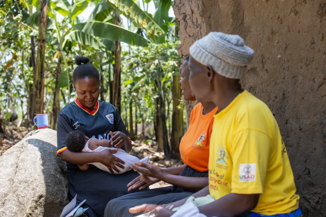 A CHEW and VHT speaks with a mother outside her home in Webuta Cell, Bumuyaga Ward, Mbale City, during a routine household visit.