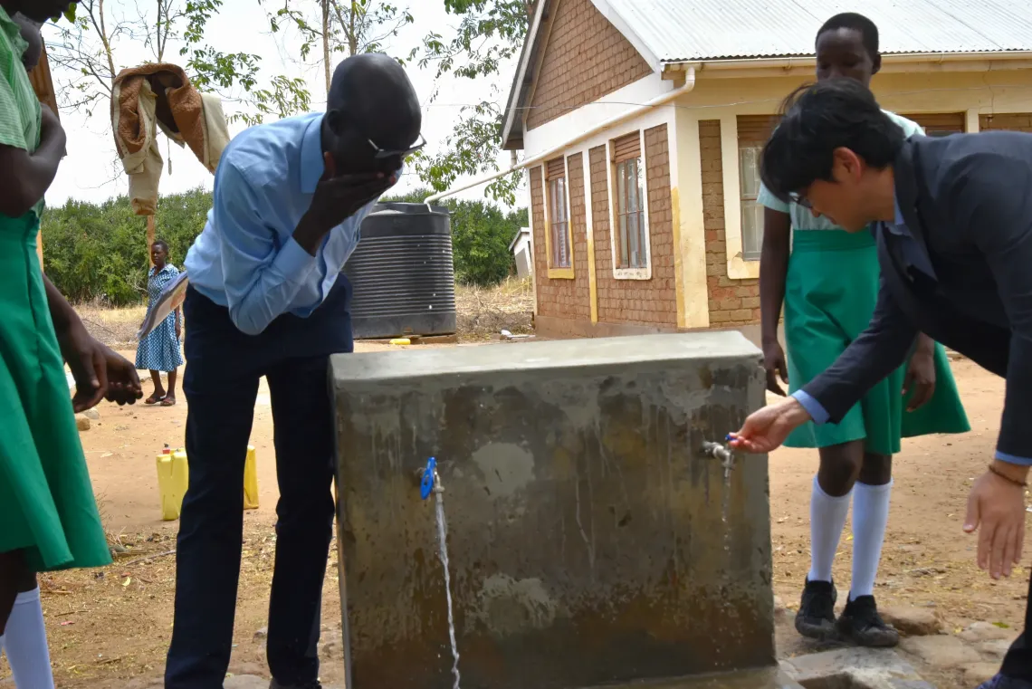 KOICA Country Director Mr Jongsu Yi opens one of the tap stands at Kalotom Primary School in Napak District during a joint UNICEF-KOICA monitoring visit. The school's solar-powered water system was restored with UNICEF-KOICA support and now provides safe and clean water to 1,259 pupils.