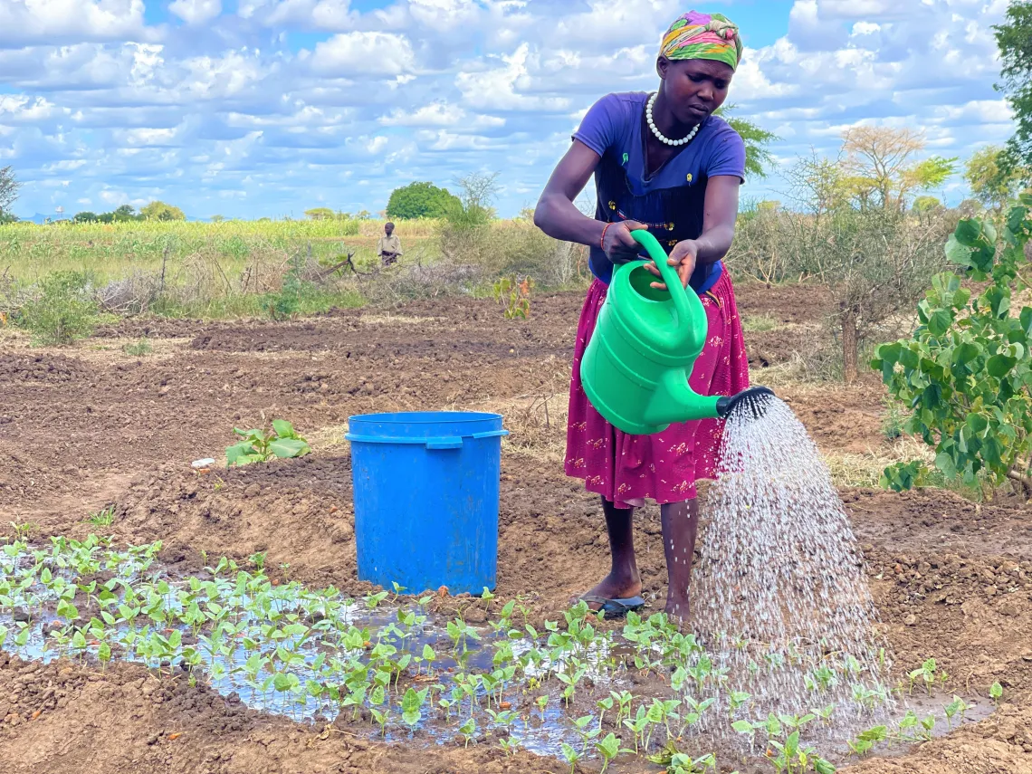 Daniel's mother irrigates her crops in the garden that she set up as a result of the UNICEF Multi-Use Water System. The community is able to boost their nutrition due to the farming done as a result of the MUWS presence.