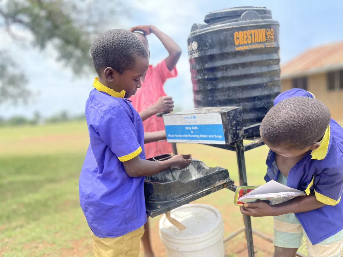 Edwin Byakatonda (left), a Primary 2 pupil at Buduma Primary School, Namayingo, using one of the five hadnwashing faciities that were supplied by UNICEF with funding from SIDA
