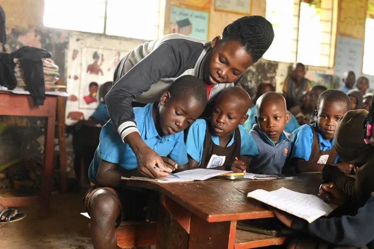 Nyamahunge Jennet, a Primary One teacher implementing the Catch-Up and remedial teaching approach at Ngangi Primary School, Kyegegwa District, assists learners during a literacy-one lesson.