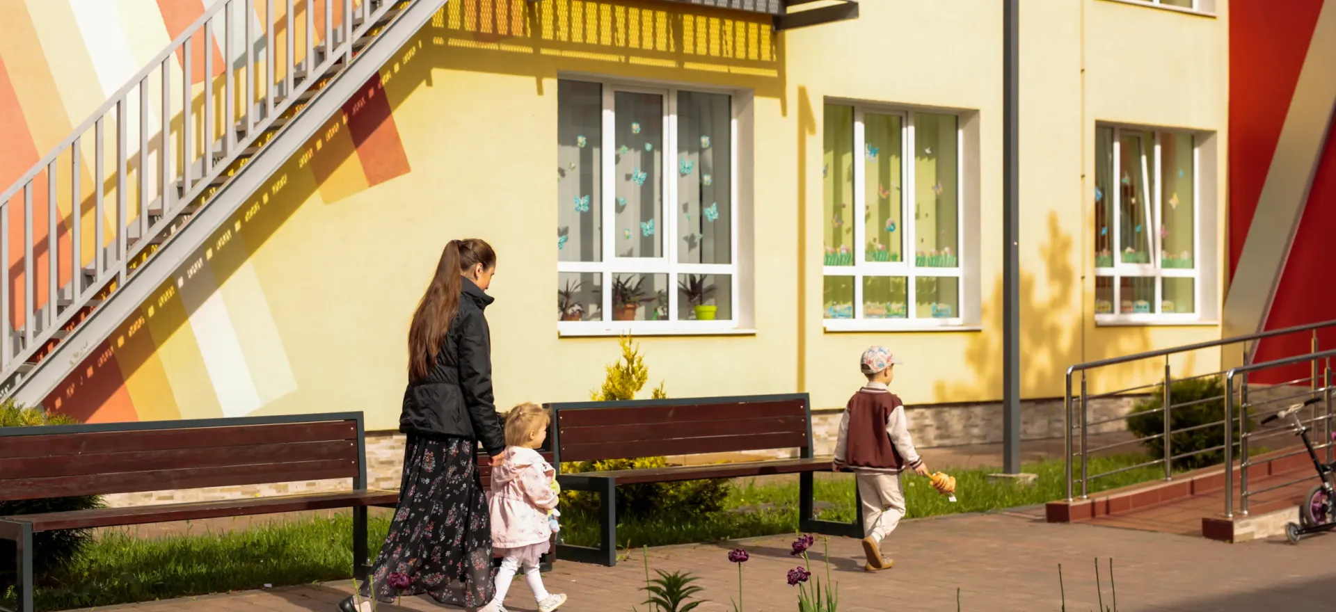 Mother taking her two kids to a kindergarten.