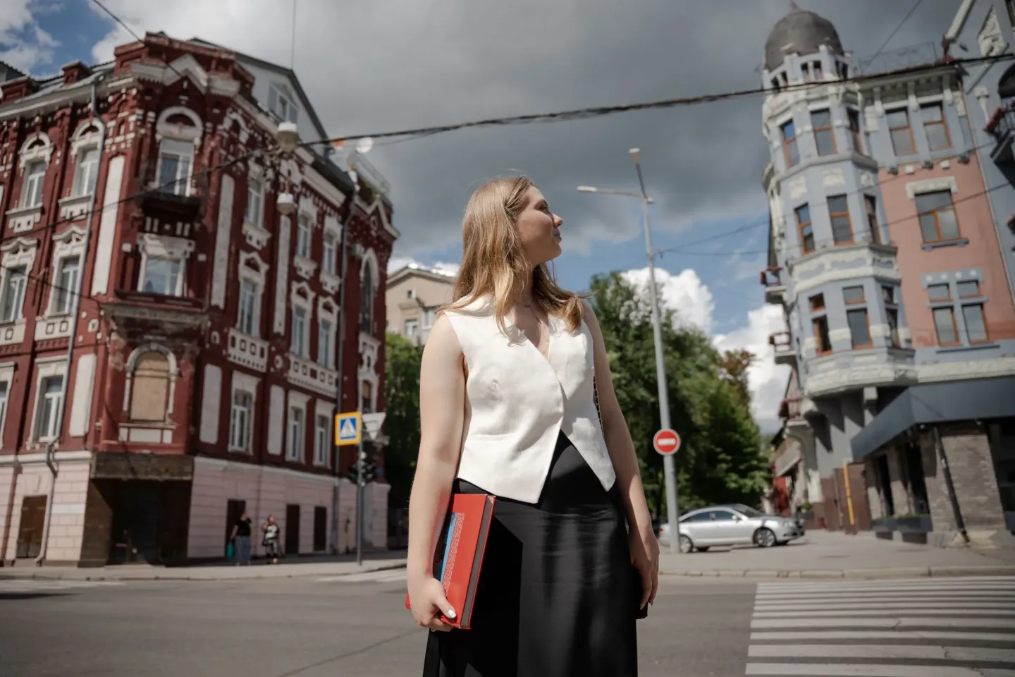 A teenage girl if walking in the city holding a book