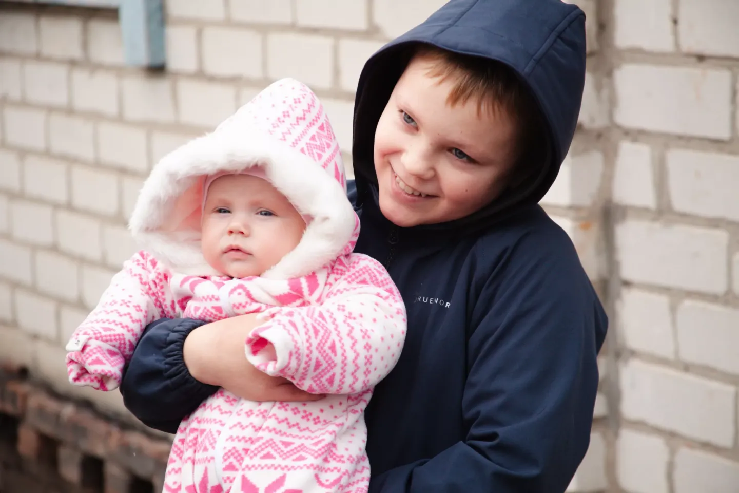 Four-month-old Dalia in her older brother's arms