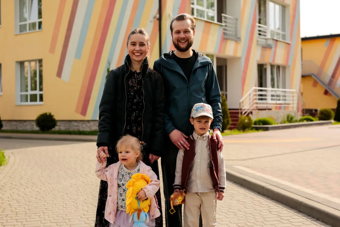 Parents with their two children standing near kindergarten
