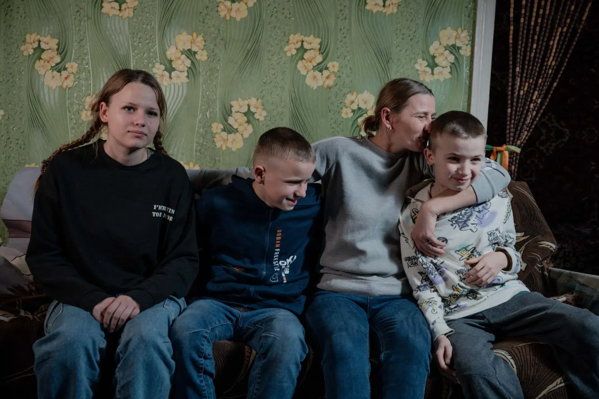 A mother and her three children sitting on the sofa at home.