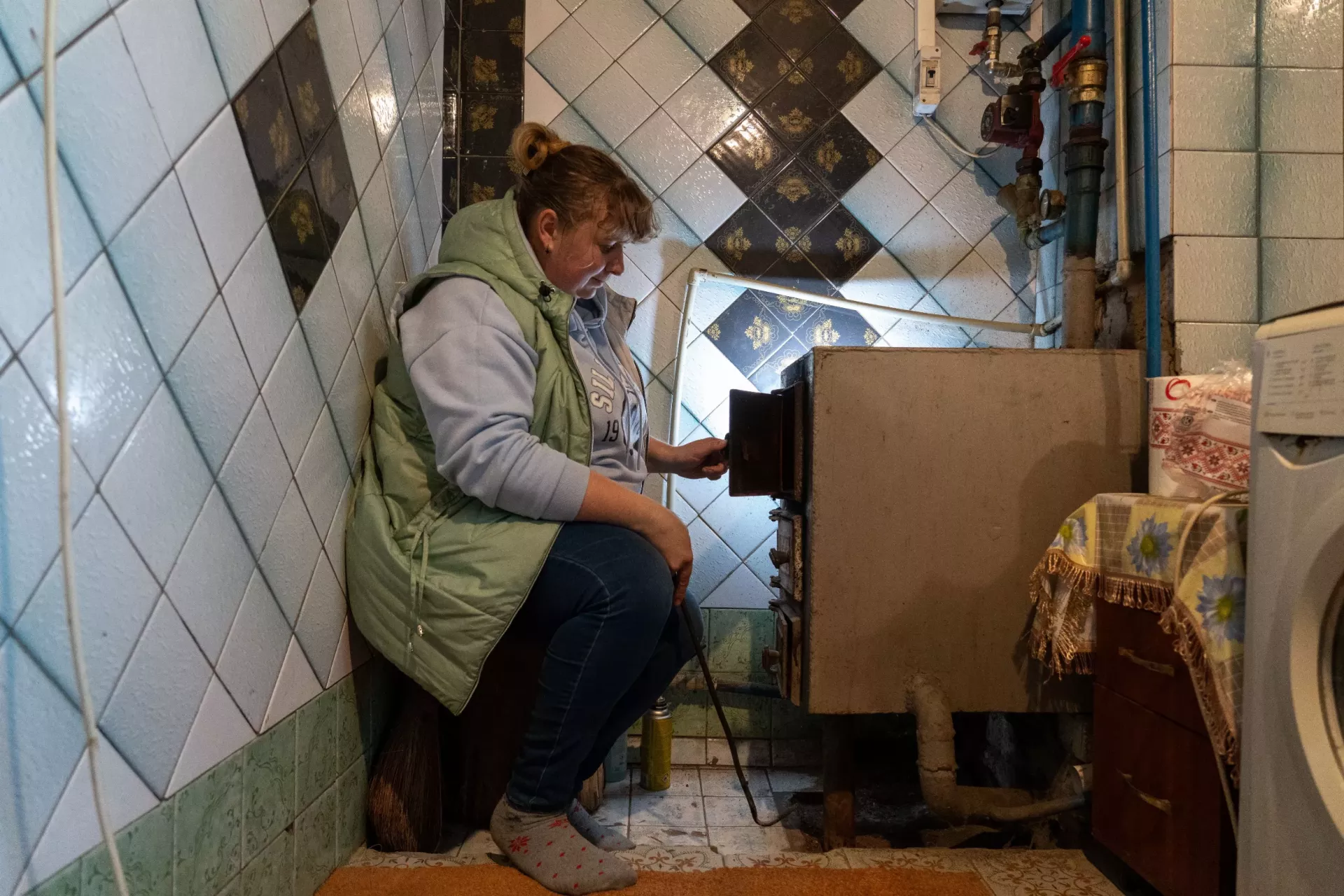 A woman is sitting neat the stove.
