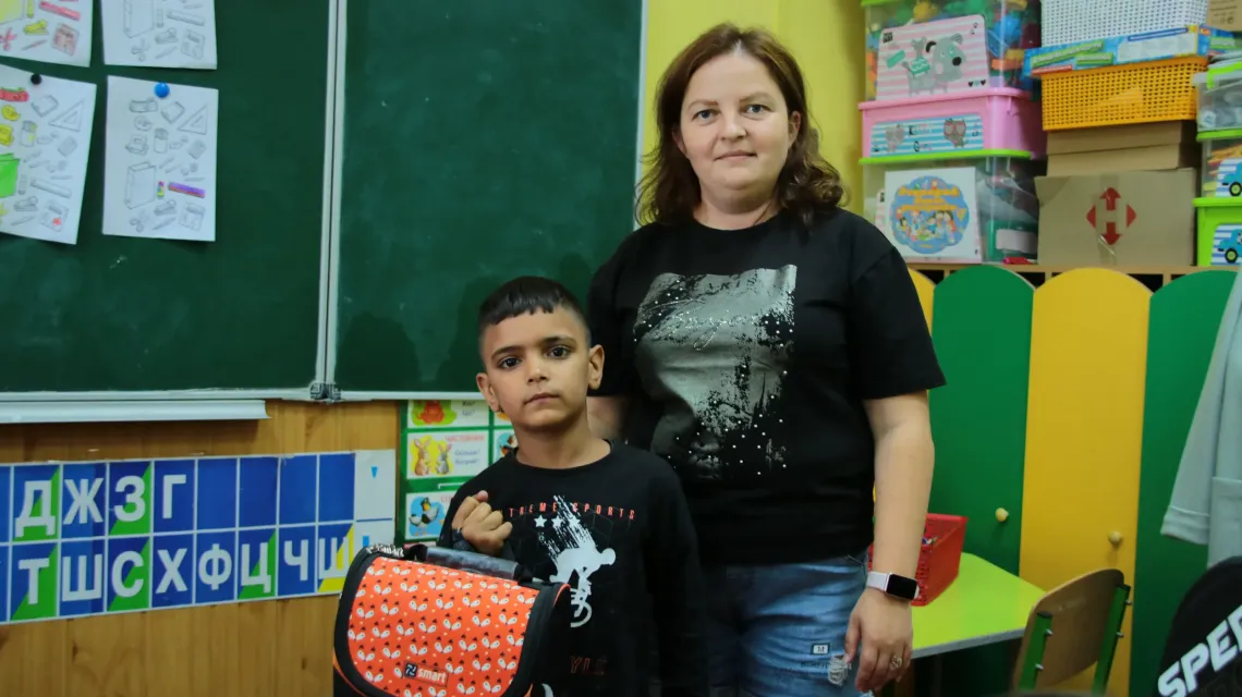 A female teacher and a boy with  a backpack
