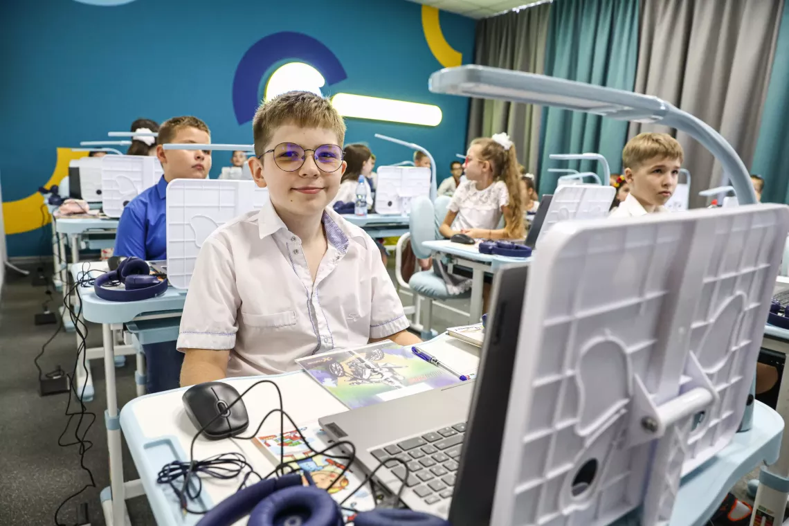 A boy sits at the computer desk at the Digital learning center