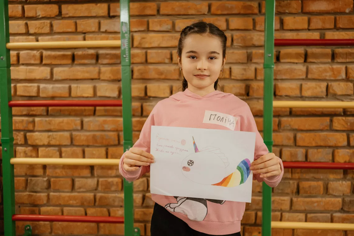 10-year-old Polina, a 5th-grade student shows her drawing. It depicts the Unicorn insect, which lives in the kitchen and eats only pink fruits - peaches, raspberries, apples