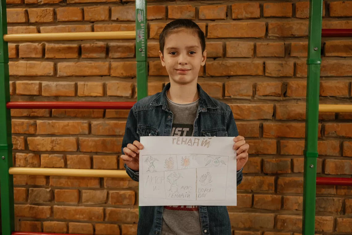 10-year-old Mykhailo, a 5th-grade pupil, shows his comic drawing about the confrontation between two insects, Gennady, who loves heat, and Voga, who loves humidity