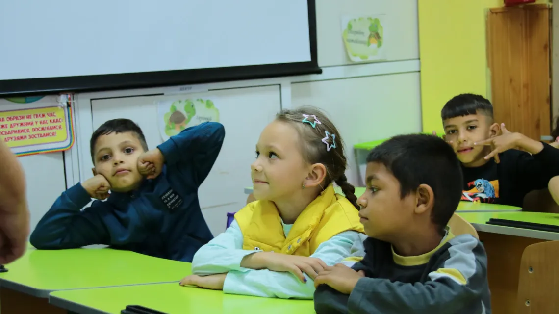 Three children are sitting in the classroom