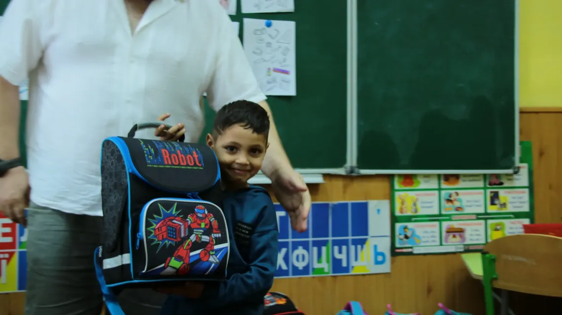  A boy is holding a backpack