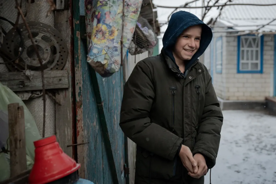 A boy stands near his house in eastern Ukraine