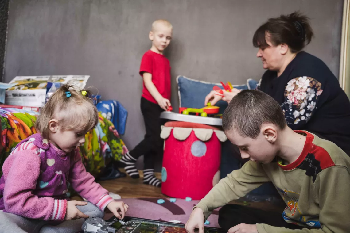 Foster parent Larysa Kirilina plays with her children: eight-year-old Matvii, seven-year-old Denys, and three-year-old Sonia.