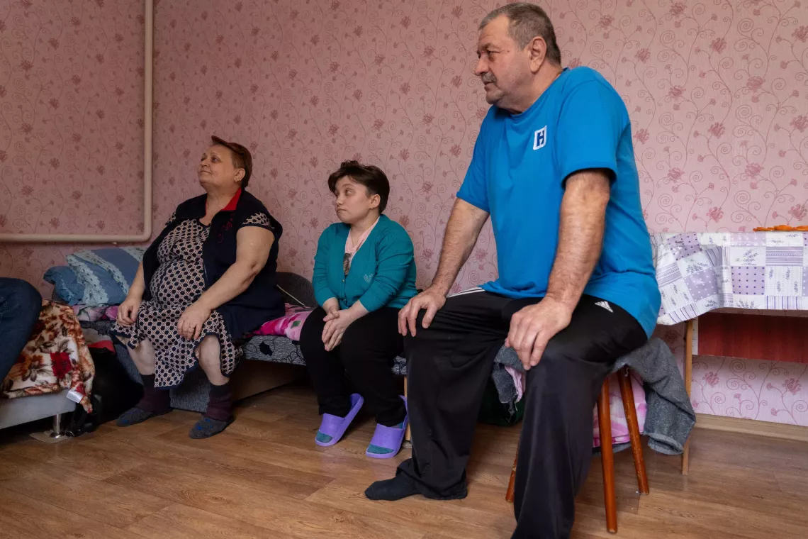 Daryna sits on the couch with her caregivers Natalia and Boris