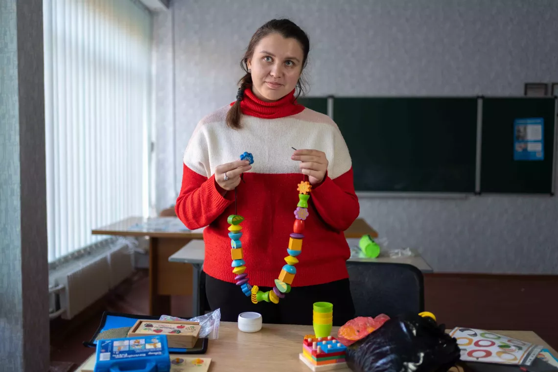 Tetiana, a child development teacher is holding wooden bricks