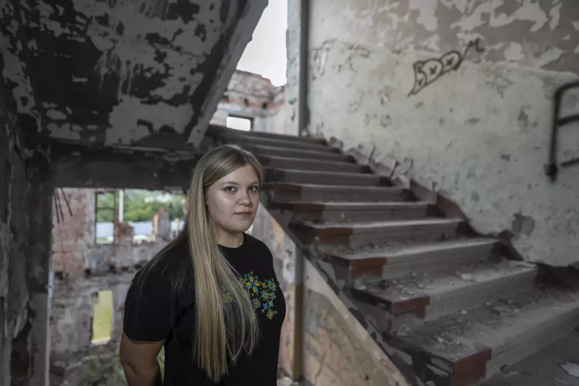 Sofiia on the stairs in a building destroyed by shelling