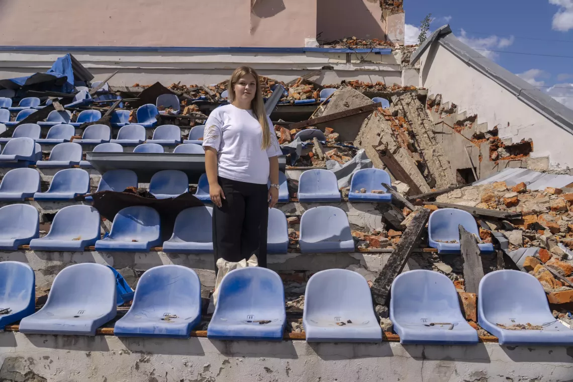 Sofia stands among broken seats in a stadium destroyed by shelling