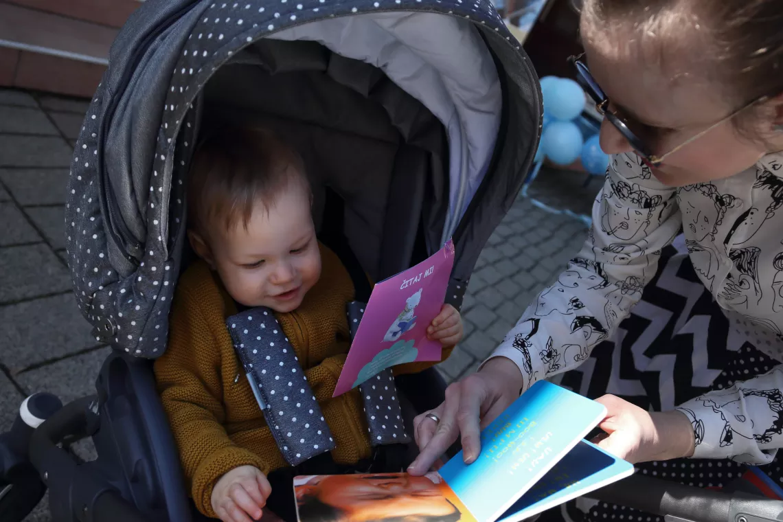 The caregiver is showing a book to the child