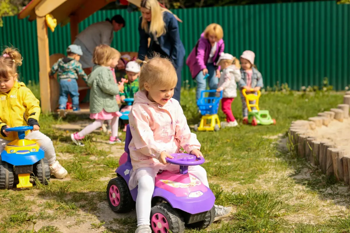 Small girl riding a toy car at the playground