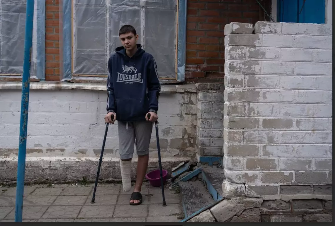 Yaroslav stands on crutches near his house