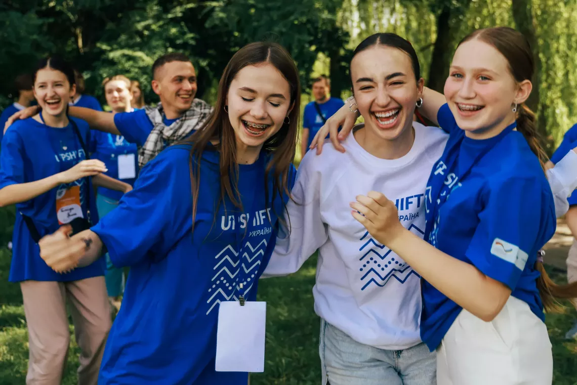 Підлітки у футболках UPSHIFT сміються і обіймаються на вулиці