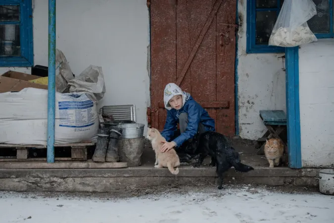 A boy and a cat sitting near the private family house in eastern Ukraine