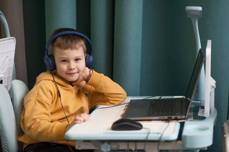 A boy is sitting at the laptop